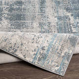 Close-up of the Stokenchurch Area Carpet showing its abstract blue, gray, and white pattern and machine-woven texture. Fold