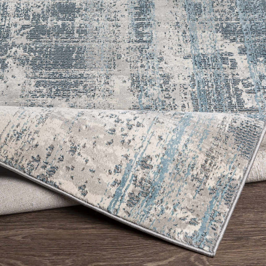 Close-up of the Stokenchurch Area Carpet showing its abstract blue, gray, and white pattern and machine-woven texture. Fold