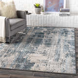 Living room scene with gray chair and Stokenchurch Area Carpet in blue, gray, and white abstract design. Roomscene-Rectangle