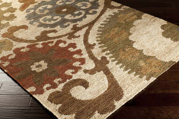 Close-up of the hand woven Stillmore Jute Area Rug. Bohemian design with brick red, olive, rust, and teal colors. Corner
