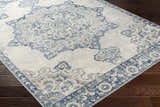 Close-up of the Stanfordville Area Rug showing its denim, gray, and ivory traditional floral pattern on dark wood floors. Corner