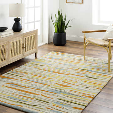 Living room scene with Aram Area Rug. Contemporary style with bronze, camel, and gray tones. Wood floors, cane cabinet, and modern chair. Roomscene-Rectangle