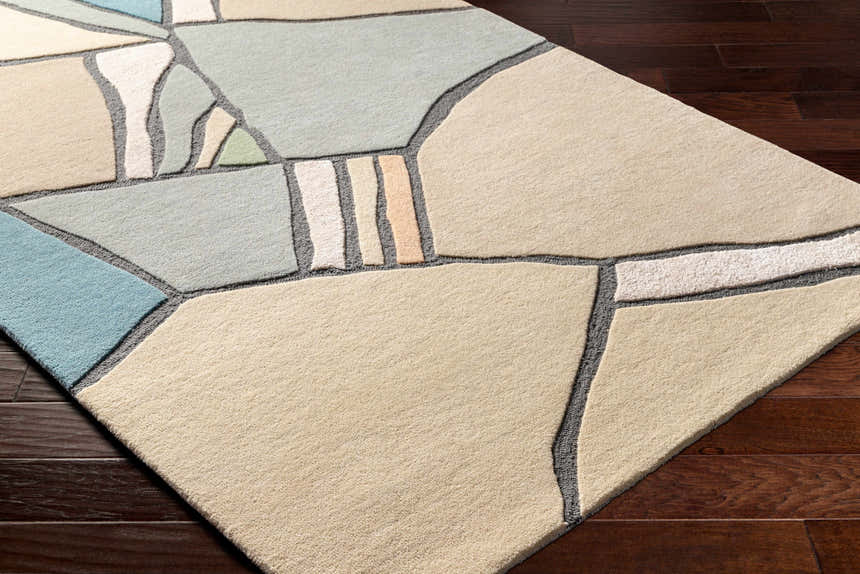 Close-up of the Ashok Area Rug featuring a geometric pattern in beige, bone, and gray tones on dark wood floors. Corner
