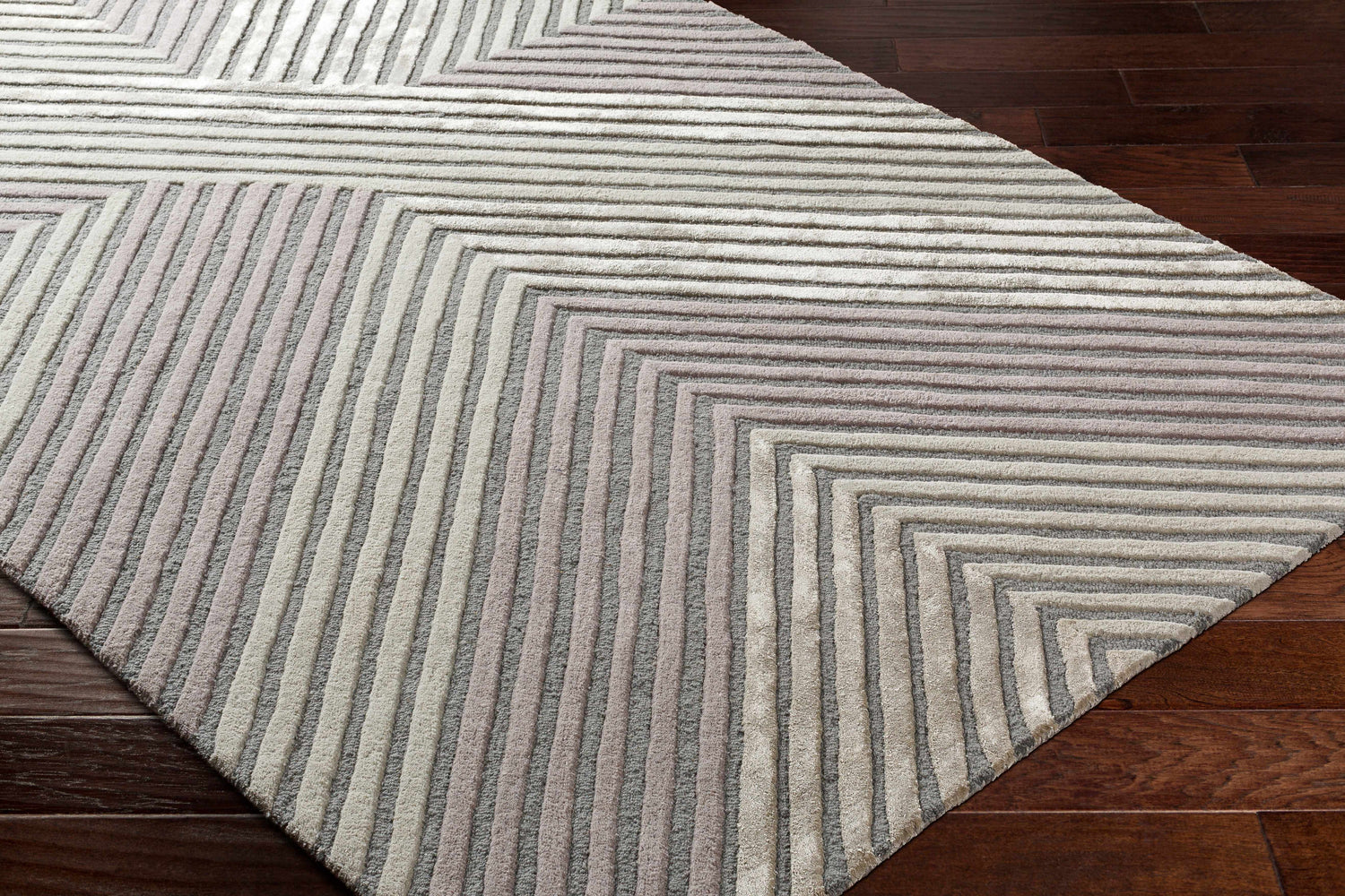 Close up of the hand tufted Juan Area Rug, featuring a contemporary geometric pattern in beige, gray, and rose cream. Corner