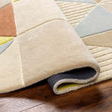 Close-up of the hand-tufted Mani Area Rug. Geometric design in camel, beige, gray, and oatmeal. Wool rug with textured pile. Fold