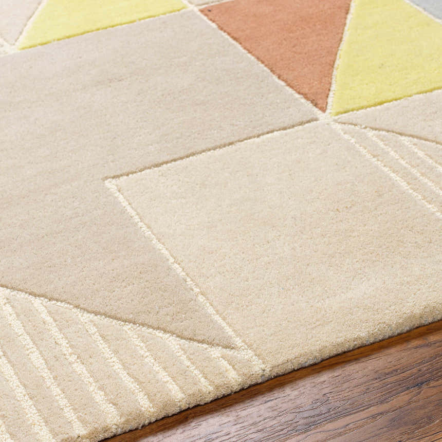 Close-up of the Mani Area Rug, a hand-tufted wool rug with a geometric pattern in camel, beige, and yellow tones. Texture