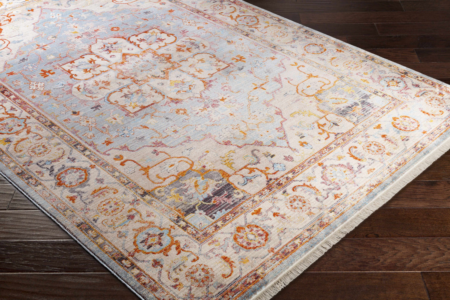 Close-up of the Stoneboro Area Rug - Clearance. Traditional design with burnt orange, light beige, and light blue hues. Corner