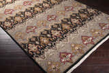 Close-up of the Stoutsville Carpet. Hand-knotted wool rug in amber, black, brick red, and ivory on dark wood floors. Corner