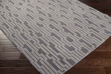 Close-up of the Eastpoint Area Carpet, a hand-knotted wool rug with a contemporary gray geometric design on dark wood floors. Corner