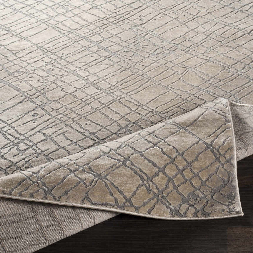 Close-up of Strykersville Area Rug. Beige rug with charcoal geometric pattern and machine woven texture. Fold