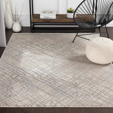 Living room scene with beige Strykersville Area Rug, black chair, and white pouf. The rug has a contemporary geometric pattern. Roomscene-Rectangle