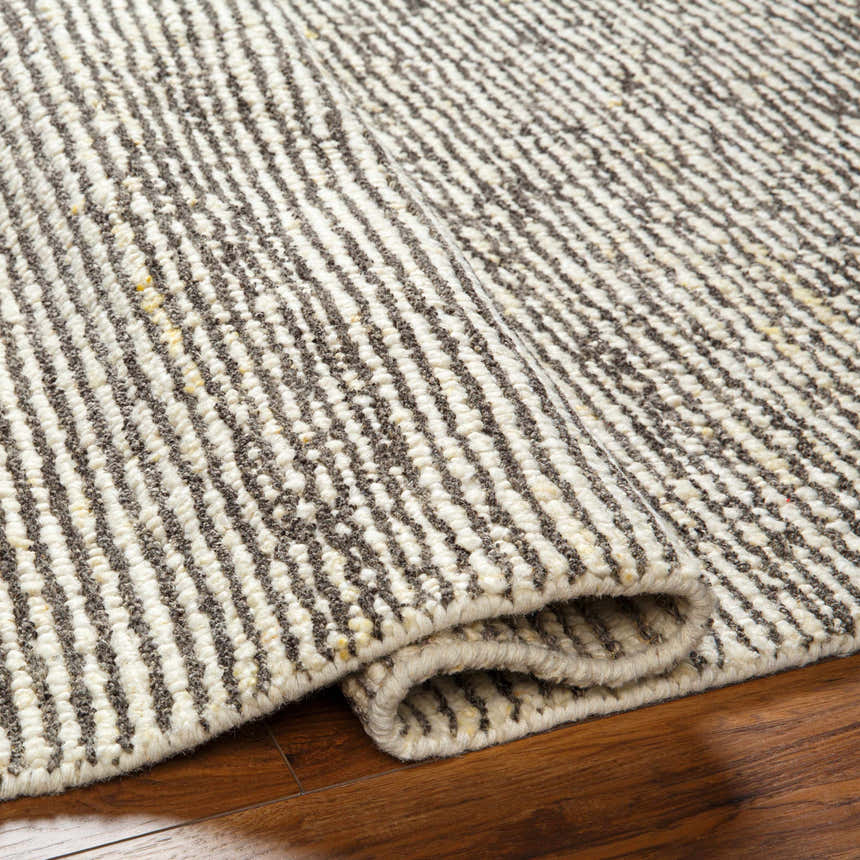 Close-up of the hand woven Caius Area Rug. Beachhouse and taupe stripes in a geometric, Scandinavian design. Fold