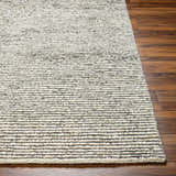 Close-up of the hand woven Caius Area Rug showing a geometric, striped pattern in beachhouse and multi brown wool. Front