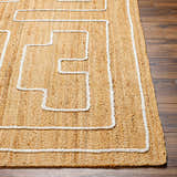 Close-up of the hand-woven Kees Area Rug. Tan jute rug with a geometric off-white pattern and braided texture. Front