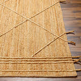 Close-up of the Zeno Area Rug showing the hand-woven jute texture, braided accents, and natural brown tones. Front