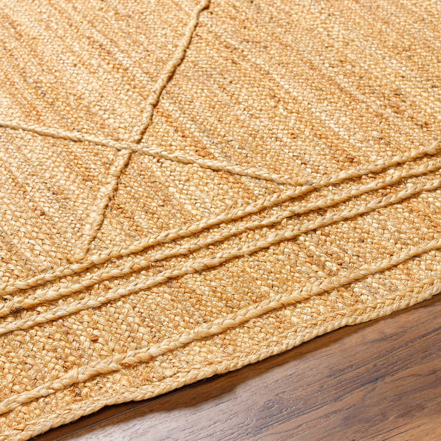 Close-up of the hand woven Zeno Area Rug. Jute rug with a braided design in natural tan and brown tones. Texture