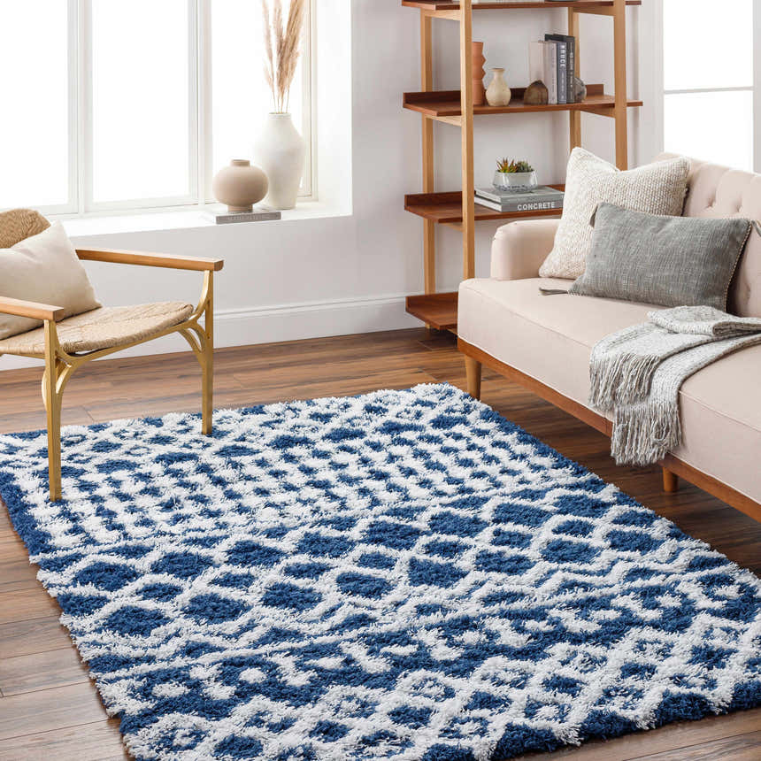 Living room scene with a blue and white geometric Suke Area Rug, beige sofa, and wooden accents. Roomscene-Rectangle