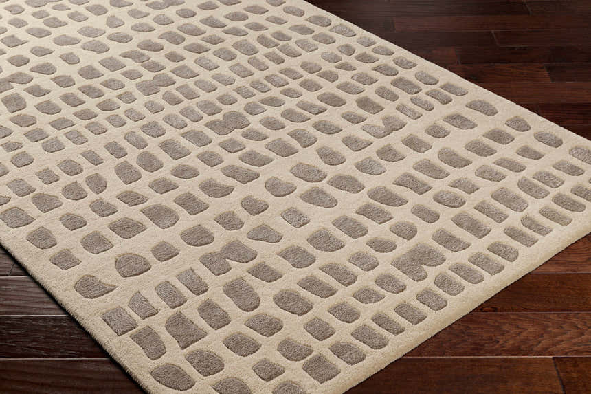 Close-up of the Arjan Beige Area Rug showing a contemporary pattern with taupe shapes on an off-white wool rug. Corner