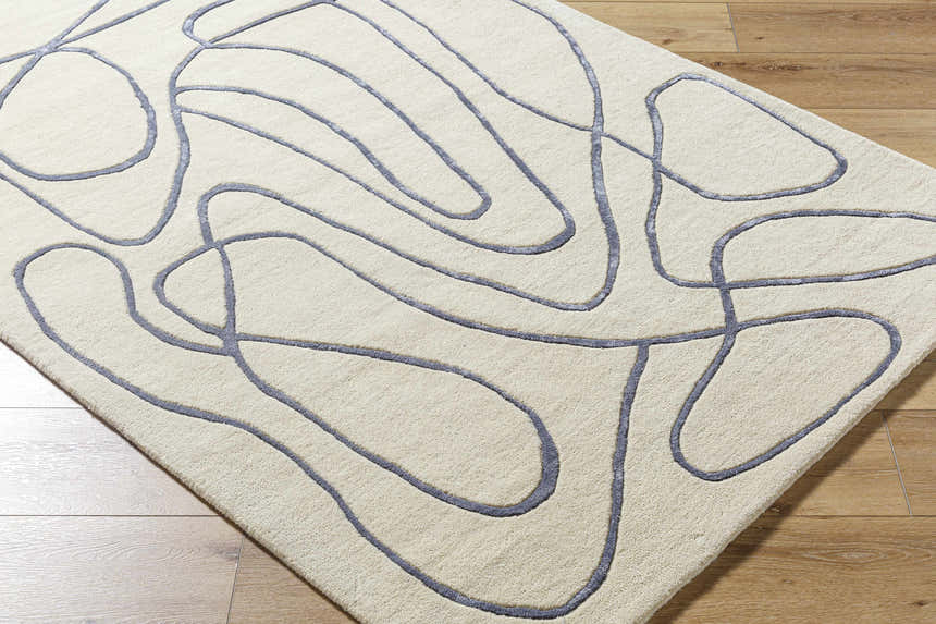 Close-up of the Derek Area Rug. Hand-tufted wool rug with a contemporary gray abstract line design on a light peach background. Corner