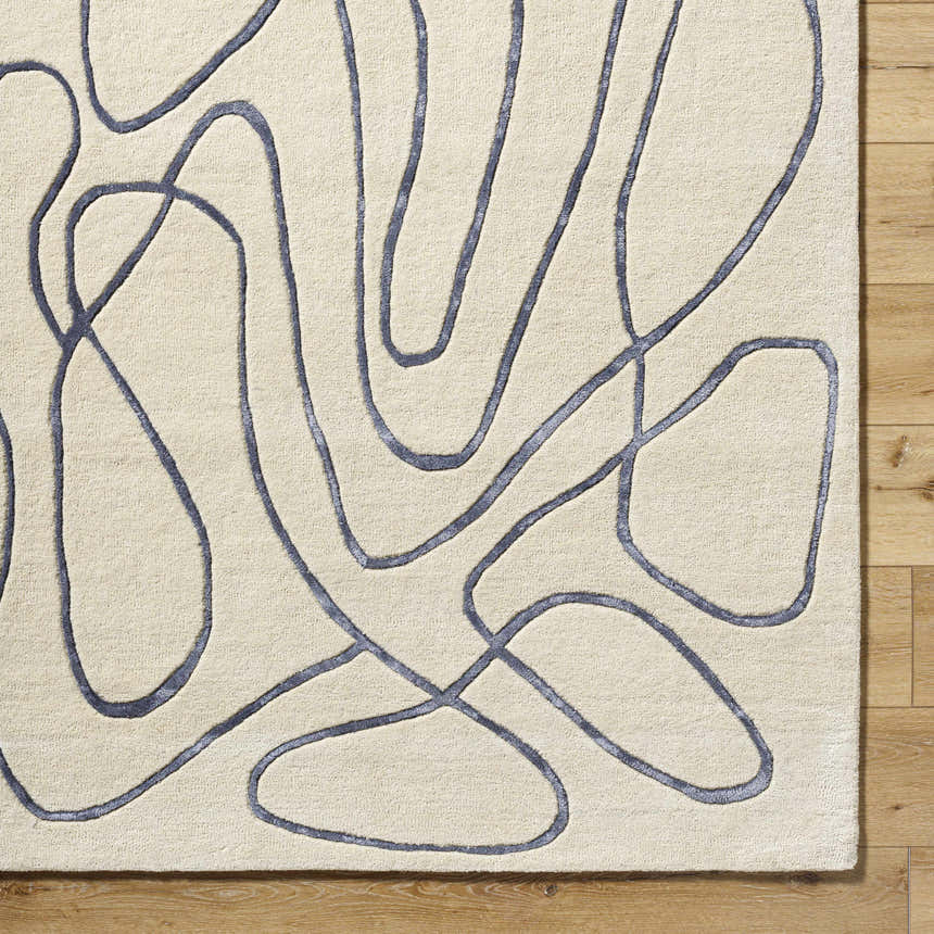 Close-up of the hand-tufted Derek Area Rug. Ivory rug with a contemporary dark gray abstract line pattern. Wool texture. Corner