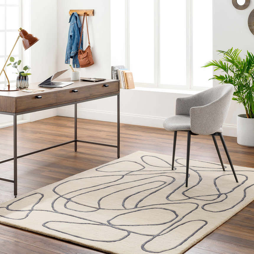 Home office with wood desk, gray chair, and Derek Area Rug featuring a gray abstract pattern on a light peach background. Roomscene-Rectangle