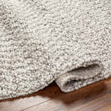 Close-up of the hand woven Chole Area Rug in natural gray, nutmeg, and smoke colors showing texture. Fold