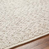 Close-up of the cloud gray Oved Area Rug showing its hand woven texture and neutral color on a wood floor. Texture
