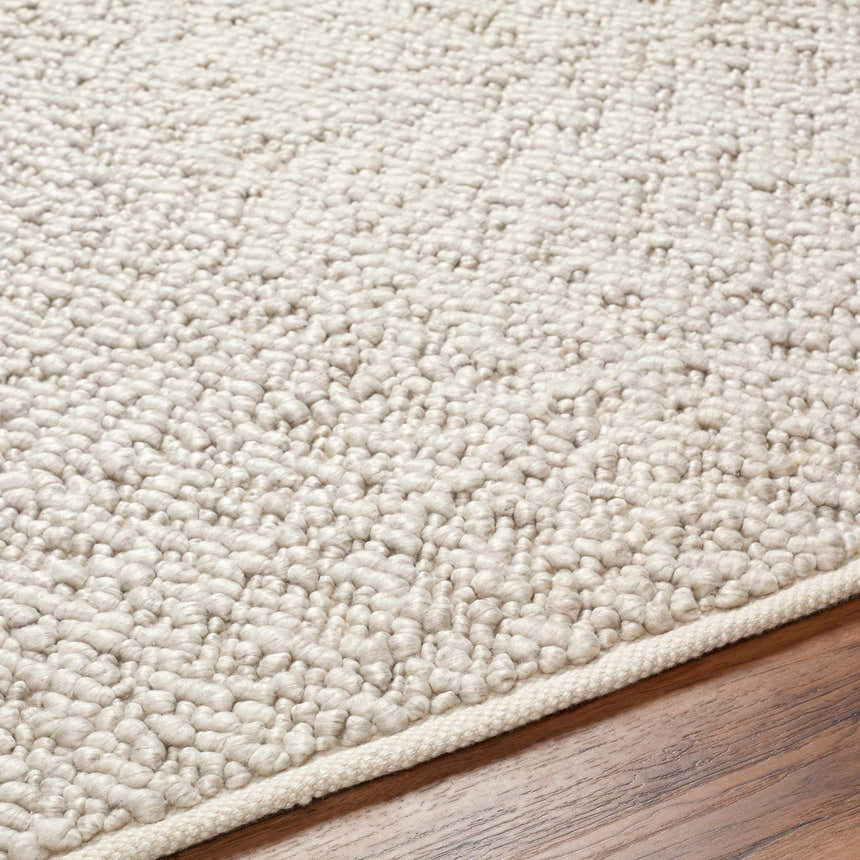 Close-up of the cloud gray Oved Area Rug showing its hand woven texture and neutral color on a wood floor. Texture