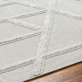 Close-up of the Cadak Area Rug showing a light gray geometric pattern with a soft, textured pile on a wood floor. Texture