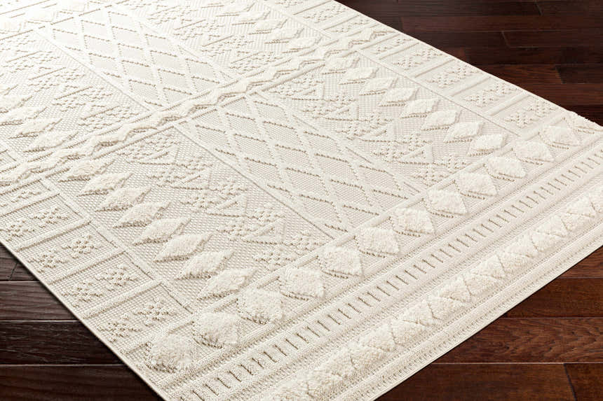 Close-up of the Elese Area Rug in beige. Contemporary style with geometric patterns and plush texture. Corner