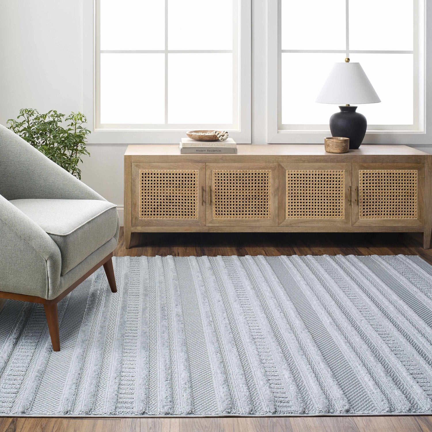 Light gray Faris Area Rug in a living room with a gray chair and wood cabinet. Roomscene-Rectangle