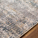 Close-up of the Sywell Luxe Fringe Rug in beige, blue, and charcoal on a wood floor. Contemporary style rug texture. Texture