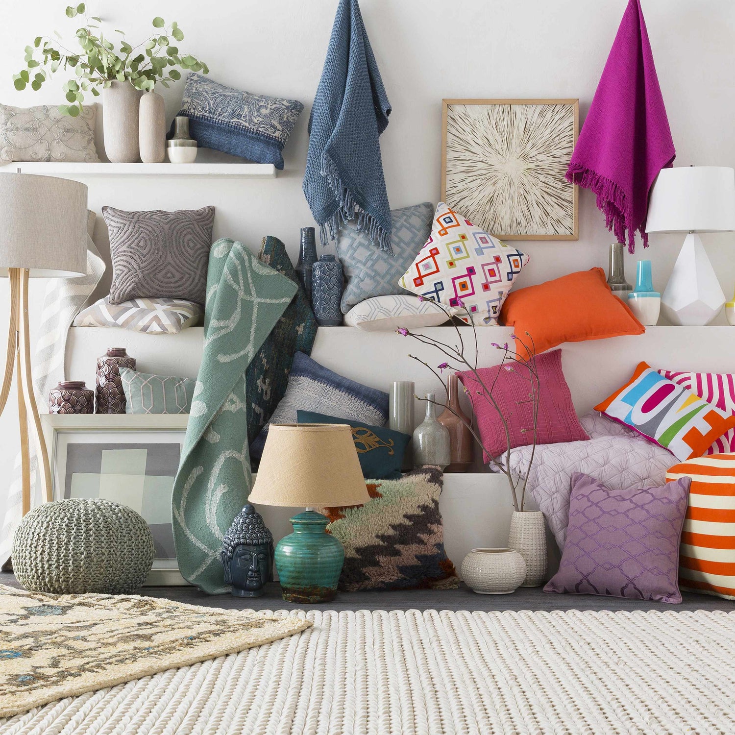 Styled home scene with a cream Christoval Area Rug, colorful pillows, throws, lamps, and vases on shelves. Styleshot
