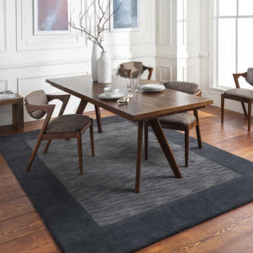 Dining room with wood table, chairs, and Bordered Solid Black Charcoal Wool Rug on wood floor. Roomscene-Rectangle