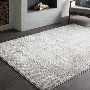 Living room with a gray armchair and Tamworth Updated Traditional Tibetan Rug in charcoal and light beige. Roomscene-Rectangle