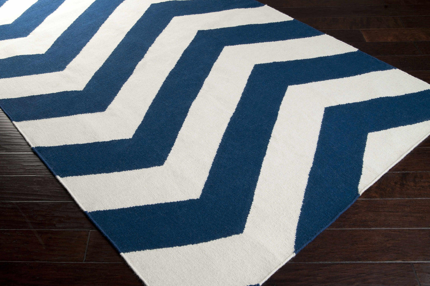 Close up of a Tamaya Area Rug. Dark blue and white chevron pattern on a hand woven wool rug. Corner