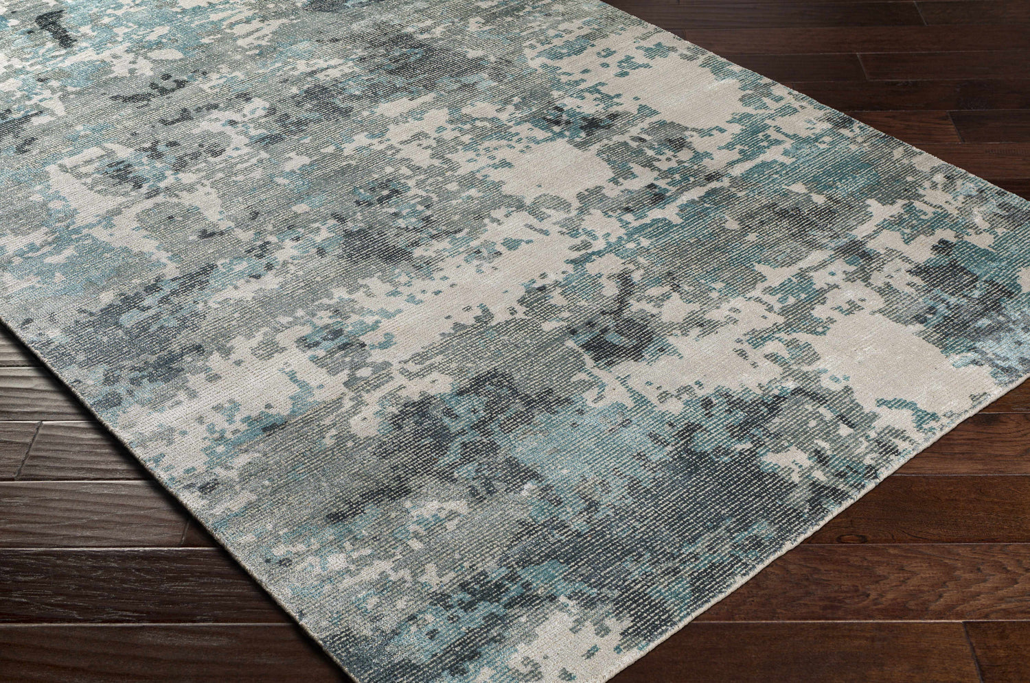 Close-up of Tannersville Area Rug: beige, sage, and teal contemporary design on dark wood floors. Corner