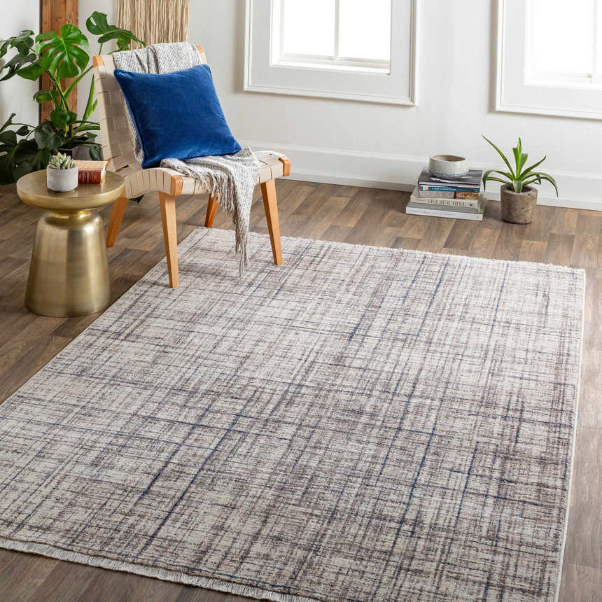 Living room scene with Taysan Area Rug in dark gray, purple, and taupe. Modern chair, plants, and wood floors. Roomscene-Rectangle