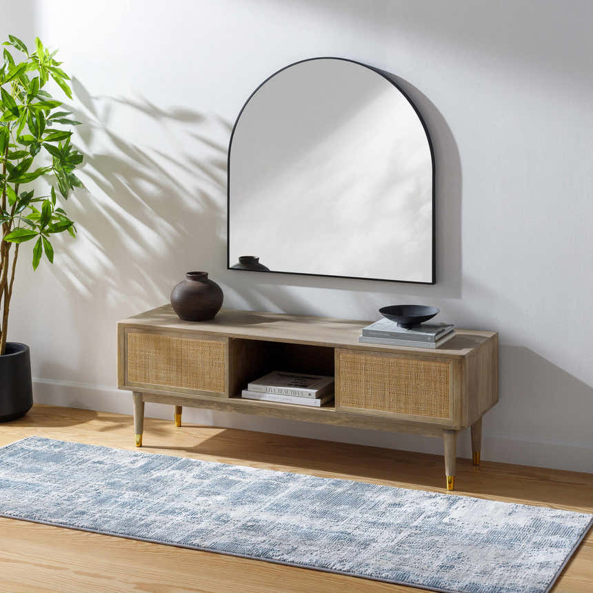 Living room scene with a blue Stokenchurch Area Carpet, wood console table, arched mirror, and potted plant. Roomscene-Runner