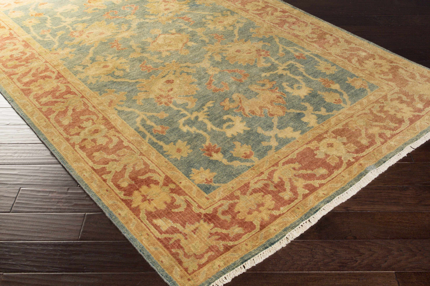 Close up of the Tchula Clearance Rug showing its camel, light green, olive, and teal floral pattern. Corner