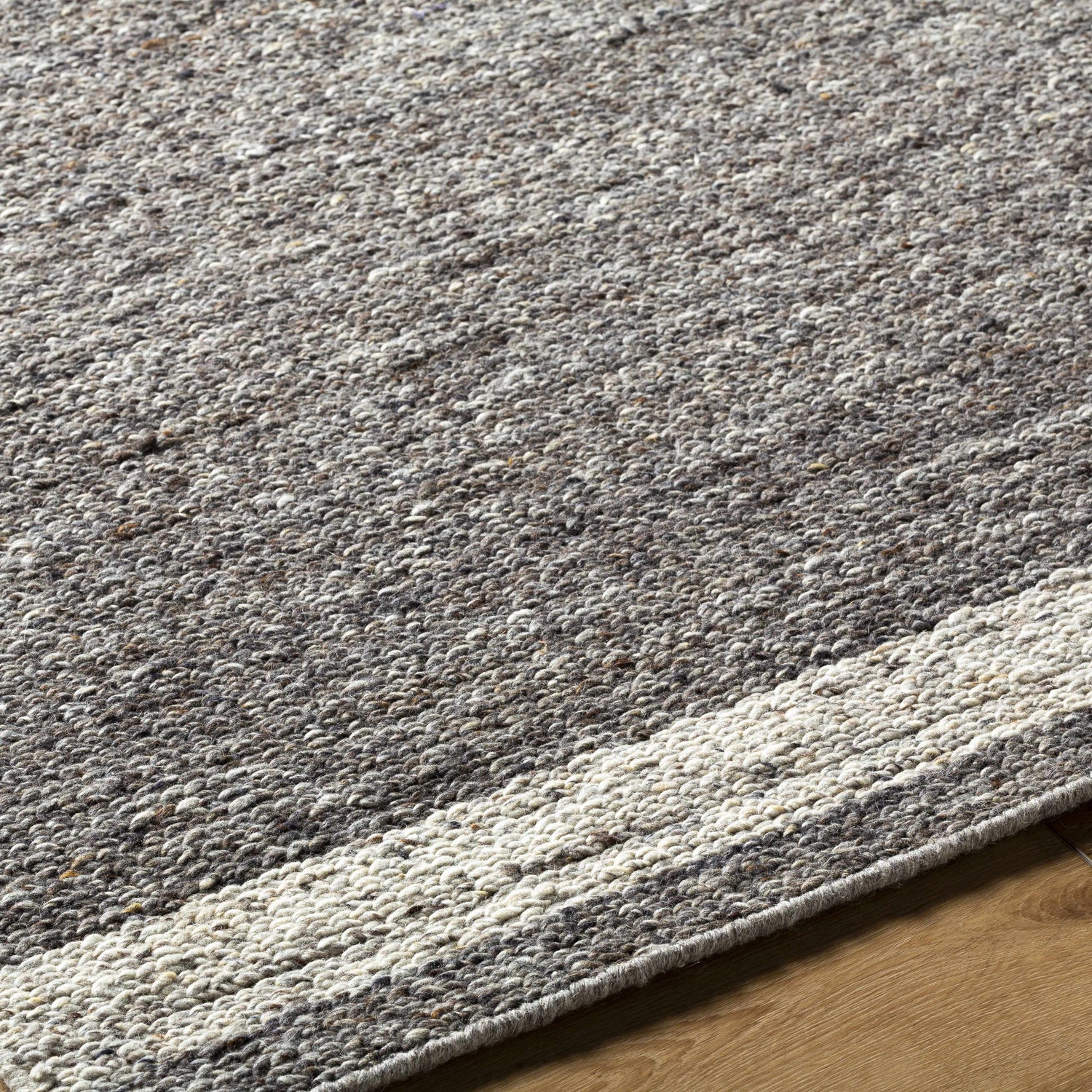 Close up of the hand-tufted Tiran Gray Wool Area Rug, showing its texture, gray tones, and subtle stripe detail. Texture