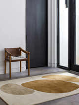 Modern entryway with a tan leather chair and the Tutti Area Rug in brick red, sepia, sterling gray, and tan. Roomscene-Rectangle