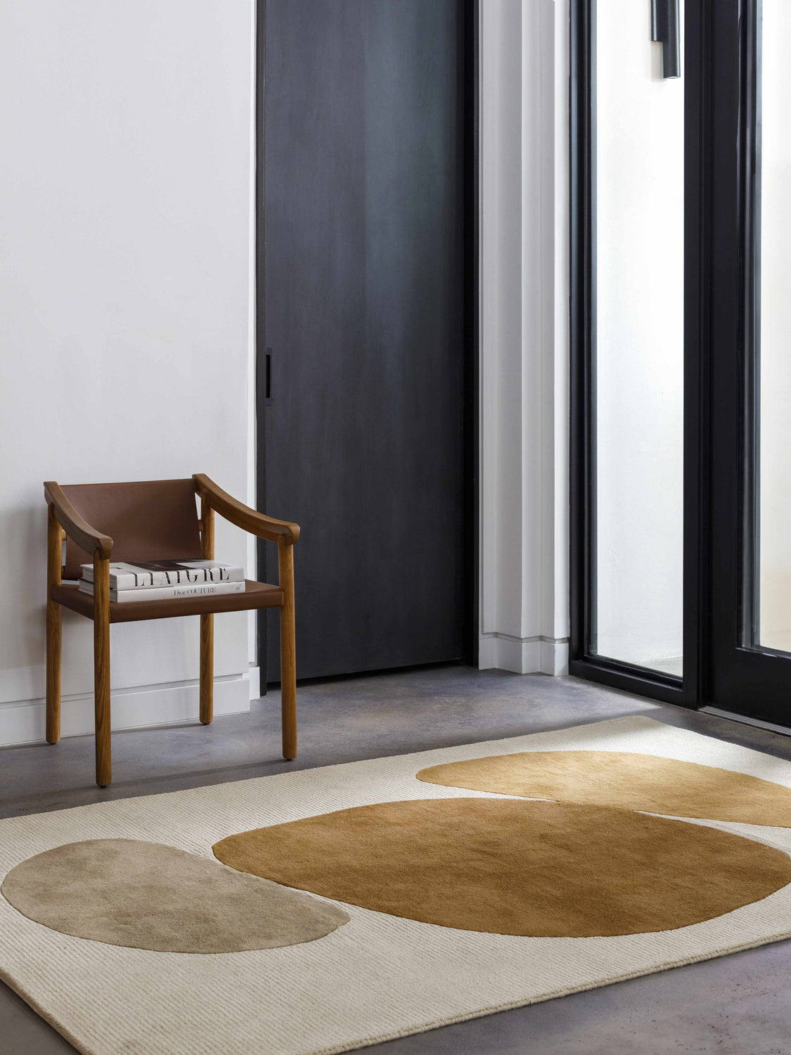 Modern entryway with a tan leather chair and the Tutti Area Rug in brick red, sepia, sterling gray, and tan. Roomscene-Rectangle