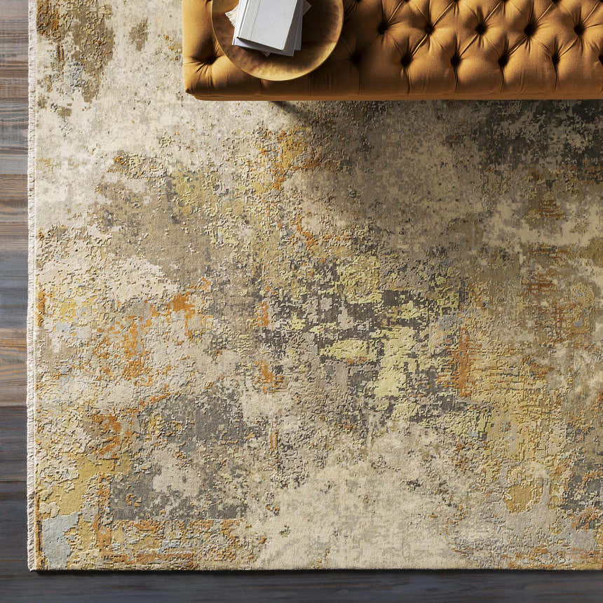 Overhead view of the Telogia Carpet. Contemporary wool rug with beige, gold, and gray distressed pattern. Tufted ottoman. Styleshot