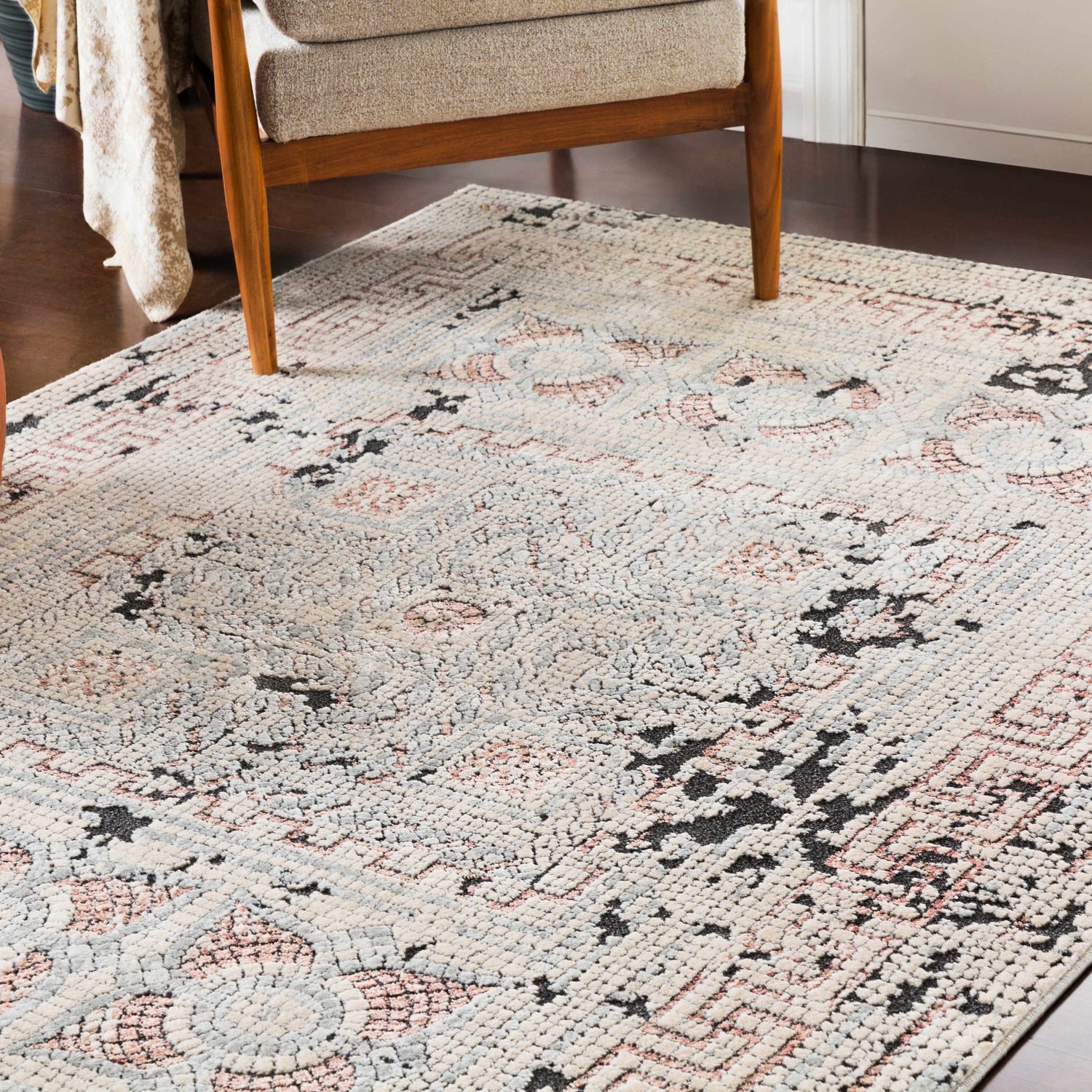 Living room scene with a beige chair on a Terlingua Area Rug. The rug has beige, black, and pastel red colors. Roomscene-Rectangle
