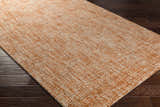 Close up of the Teresita Area Rug in burnt orange and ivory, a hand tufted wool rug on dark wood floors. Corner