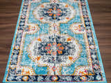 Close-up of the Tigried Turquoise 2308 Area Rug. Features a bohemian-style design with blue, ivory, and orange accents. Corner