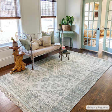 Sunlit living room with a sage green Undy Handmade Cotton-blend Rug, daybed, and light blue French doors. Roomscene-Rectangle