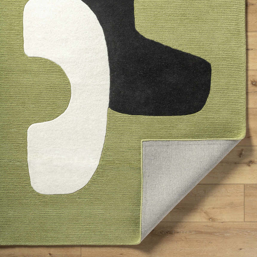 Close-up of the hand-tufted Terah Olive Area Rug. Features jet black, light silver, and moss abstract shapes on a wool rug. Fold