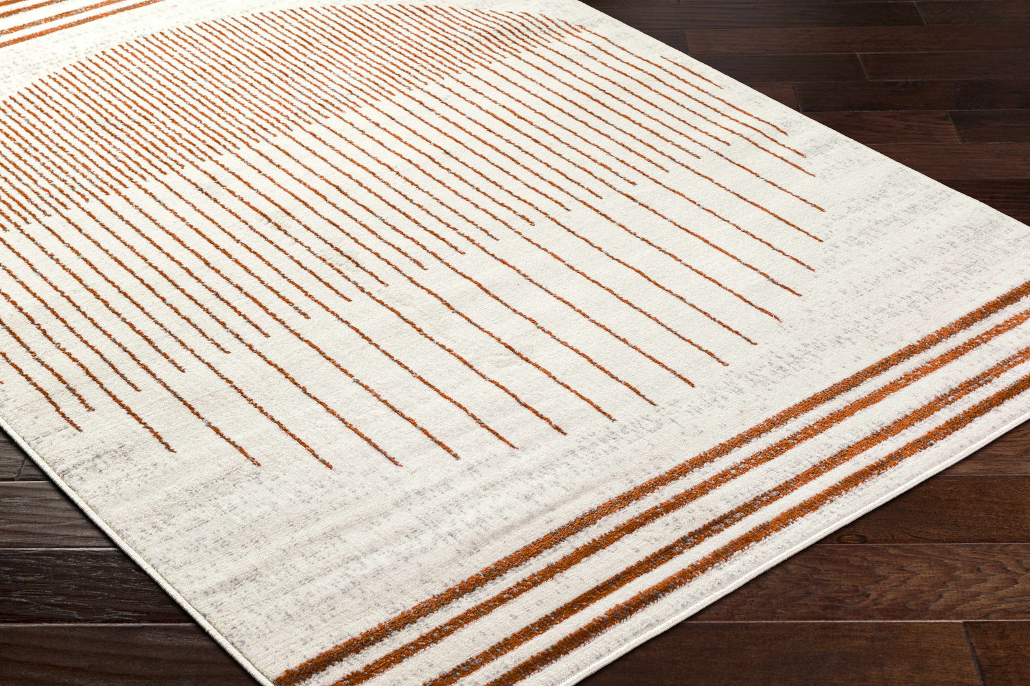 Close-up of the Thono Area Rug showing burnt orange linear design on a light gray background. Corner